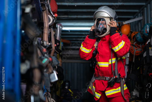 Firefighter wearing protective clothing and breathing equipment prepares a helmet