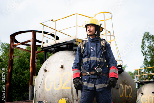 Cuadro en lienzo Firefighter wearing protective gear and breathing apparatus stands beside indust