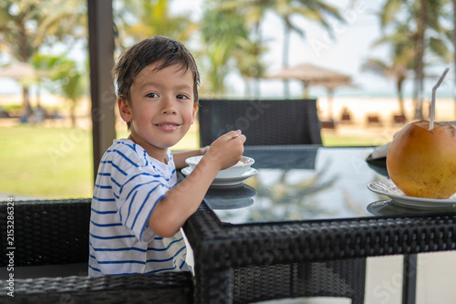 Multiracial boy enjoying breakfast at a seaside café in Sri Lanka