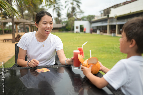Woman shares refreshing drinks with young boy at outdoor restaurant in Sri Lanka