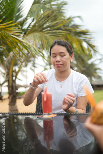Relaxing beachside atmosphere with Asian woman enjoying a fruity drink