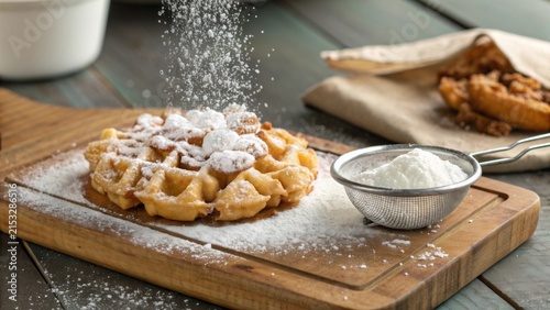 Delicious funnel cake topped with powdered sugar on a rustic wooden board at a local fair