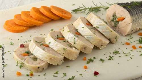 Sliced gefilte fish served with carrot garnishes on a neutral background for a traditional Jewish meal