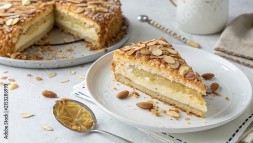 German bienenstich cake sliced on a plate with almonds and cream filling displayed on a table in a cozy setting