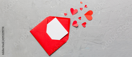 Red paper envelope with empty white card and heart on colored background. top view valentines day concept