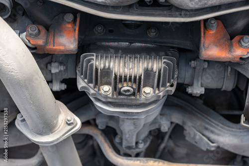 Close up view of a finned rear differential housing, subframe mounts, and exhaust flange connection on an elevated vehicle.