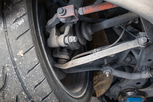 Obraz na plátne Close up view of a rear suspension linkage assembly, drive axle CV boot, and semi-slick tire mounted on a raised vehicle