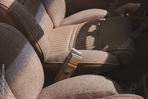 Close up view of retro tan fabric seat upholstery and seatbelt buckle in vintage convertible car interior.