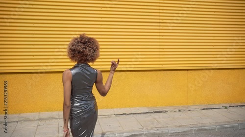 A Stylish Woman Posing Confidently and Elegantly Against a Bright Yellow Background