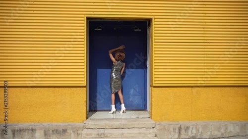 A Fashionable Woman Posing Stylishly in Front of a Bright and Cheerful Yellow Wall