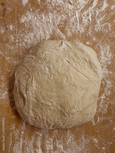 фотографія Homemade yeast dough ball for pies on a floured wooden surface, fresh raw pastry
