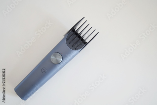 Electric hair trimmer with long comb attachment on plain white surface