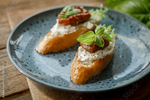 Bruschetta or crostini with feta, sun-dried tomatoes, olives and fresh herbs. Tasty healthy snacks for breakfast