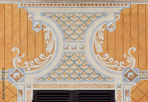 Traditional Ligurian trompe l'oeil fresco painting decoration on a yellow house facade above a window shutter in Camogli, Italy