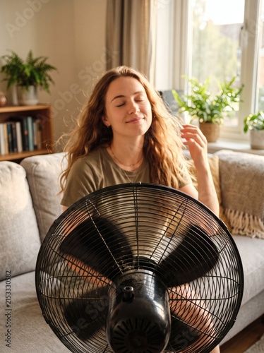 Young woman cooling off in front of an electric fan