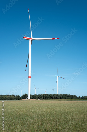 Wind turbines stand tall in a green field under a clear blue sky