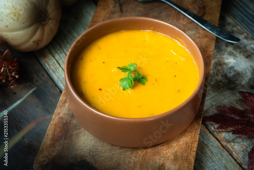 Pumpkin puree soup decorated with a sprig of fresh parsley. Rustic vibe.