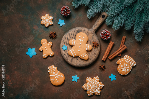Gingerbread cookies with Christmas decorations on dark brown grunge background, top view, flat lay