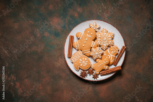 Gingerbread cookies in a plate on dark brown rustic background, collection of homemade gingerbread cookies with cinnamon and star anise, top view, flat lay, copy space.