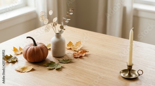 Small pumpkin and candle with autumn leaves on a dining table