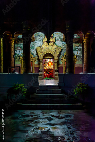 LUANG PRABANG, LAOS – A Buddhist temple shrine glows with candlelight and golden statues at night in Luang Prabang, where evening prayer ceremonies continue a centuries-old spiritual tradition.
