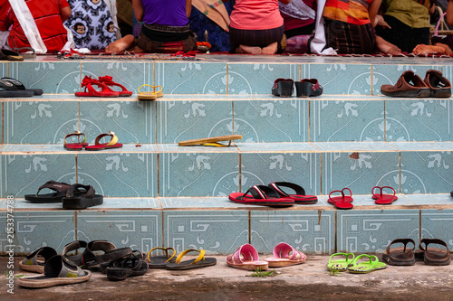 VIENTIANE, LAOS – Rows of sandals and shoes sit outside a Buddhist temple entrance in Vientiane, following the Laotian custom of removing footwear before entering sacred spaces.