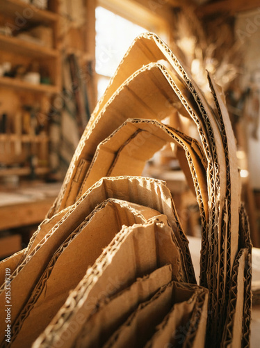 Stack of corrugated cardboard sheets piled inside a rustic workshop with shelves