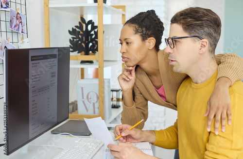 Couple reviewing bill at computer, budgeting payment. They review details, manage utilities and household finances, planning due dates to grow savings. Clear concept of home finance.