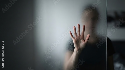 Person standing behind frosted glass pane with hand pressed against surface with moody mysterious atmosphere mental health water drops out focus introspection condensation concealment isolation