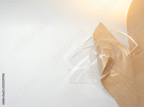Transparent acrylic forms beside curved wooden panel in warm directional light