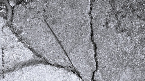 A black-and-white close-up of a stone surface featuring intersecting cracks, a granular texture, and weathered details suitable for industrial, urban, or abstract-themed backgrounds.