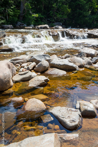 Swift River cascading over a rocky ledge into clear wading pools at the Lower Falls Scenic Area in White Mountain National Forest, New Hampshire.