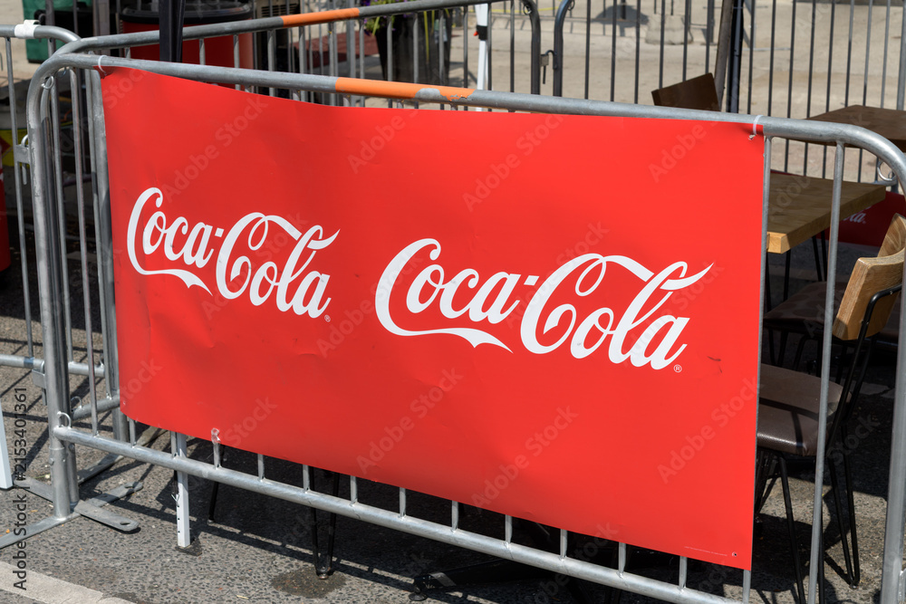 Fototapeta premium Coca-Cola sign pinned to a crowd control barrier fence on the Danforth, Toronto