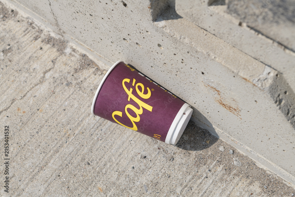 Fototapeta premium discarded McDonald's Canada McCafé beverage cup on a concrete pavement next to a concrete wall in Toronto