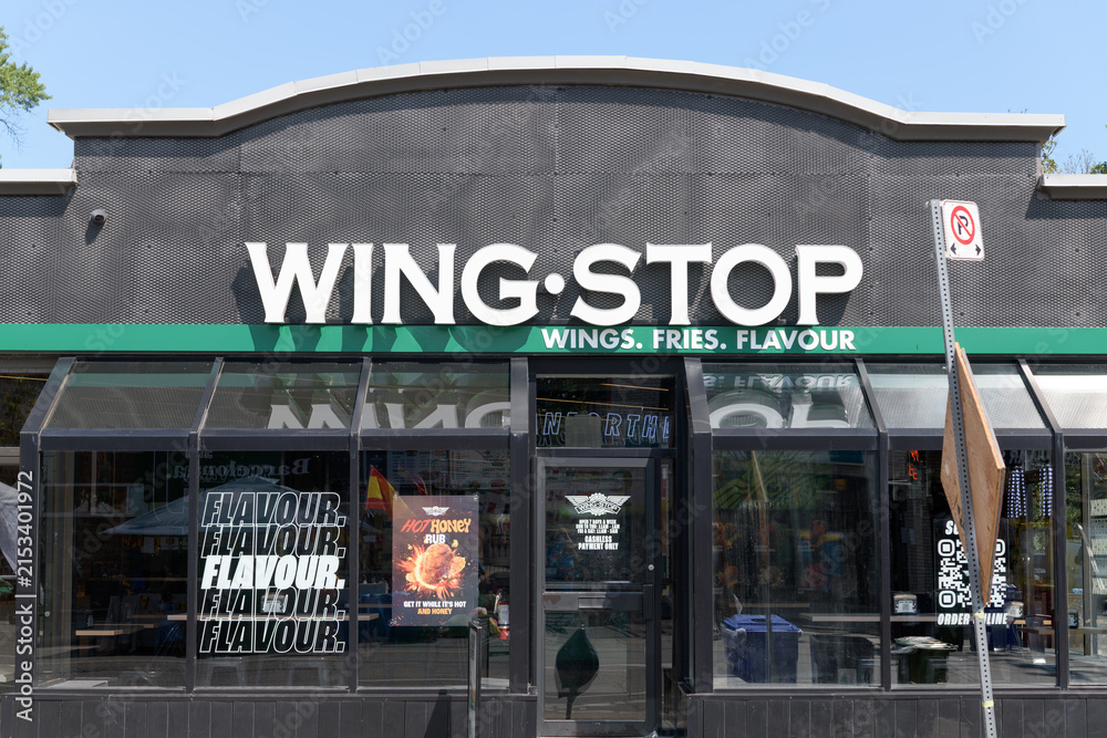 Fototapeta premium exterior building facade and sign of Wingstop, a chicken wings restaurant, located here at 780 Danforth Av, Toronto