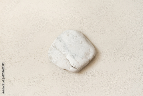 White natural stone with irregular shape and rough surface texture placed in the lower right corner of a clean light neutral background, with open copy space for cosmetic advertising