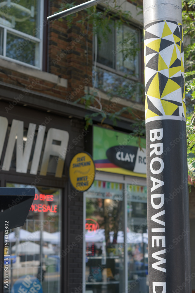 Fototapeta premium Broadview Danforth BIA pole wrap and defocused businesses on Danforth Av near Broadview Av, Toronto