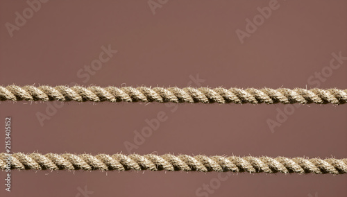 Two twisted ropes horizontal line against brown background