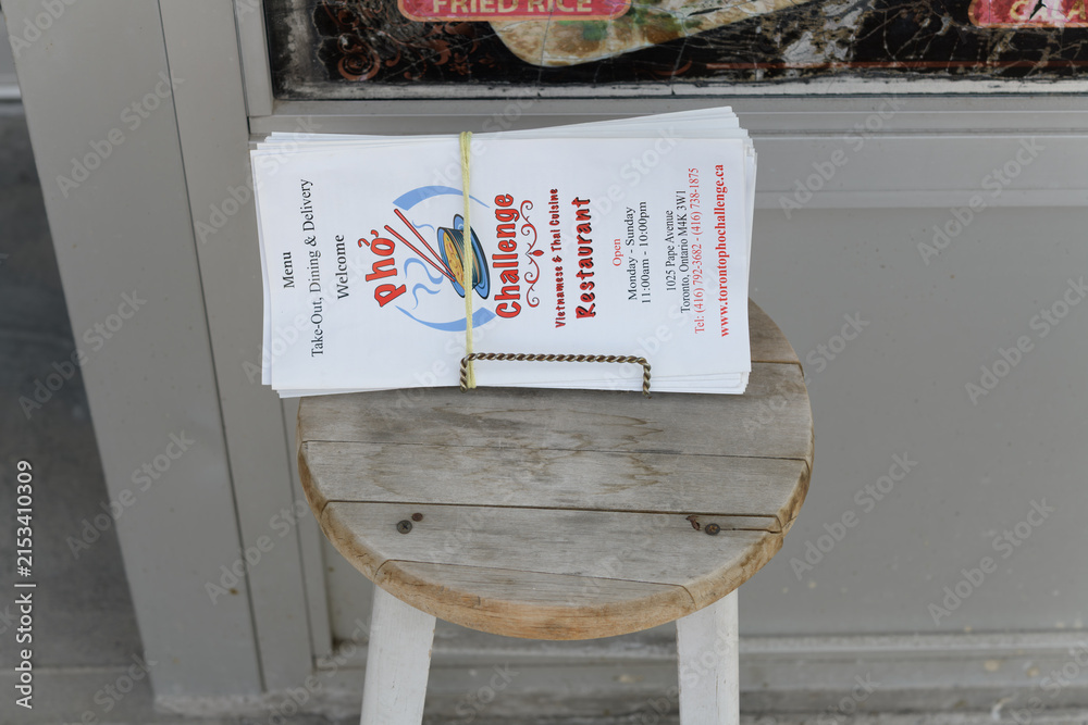 Fototapeta premium old wood stool with a packet of menus outside Pho Challenge, a Vietnamese restaurant, located at 1025 Pape Av (East York), Toronto