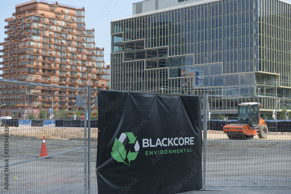 Fototapeta premium Blackcore Environmental banner at a construction site south of Lake Shore Blvd E with defocused view of Aqualuna Condos and T3 Bayside corporate office, Toronto