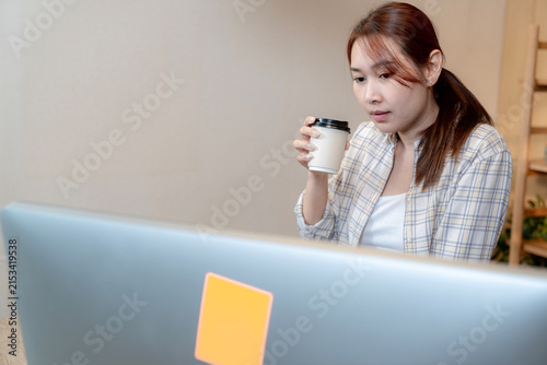 A freelance woman sitting at a desk and working on her laptop computer in a home office setting.
