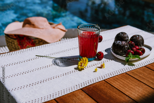 Refreshing organic fruit drink with fresh cherries and plums on poolside terrace