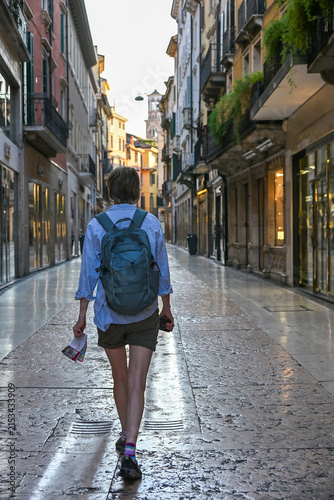 Lone traveller walking through a quiet street in historic Verona, Italy