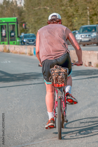 A woman rides a bicycle on a sidewalk on a summer day