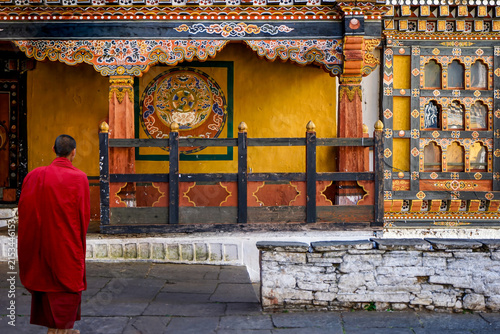 Bhutan, Paro, a monk in his red dress walks inside the rich decorated Rinpung Dzong.	