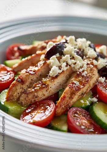 Grilled Chicken Breast Greek Salad with Cucumber, Cherry Tomatoes, Feta and Kalamata Olives on a White Ceramic Plate