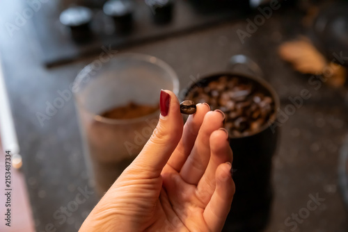 Bild auf Leinwand Woman holding a roasted coffee bean beside a cup and bowl of beans