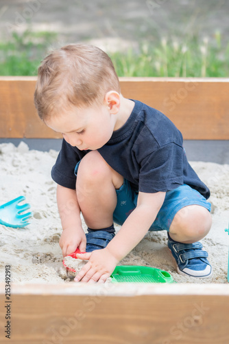 Little child developing creativity through play with sand and toys.