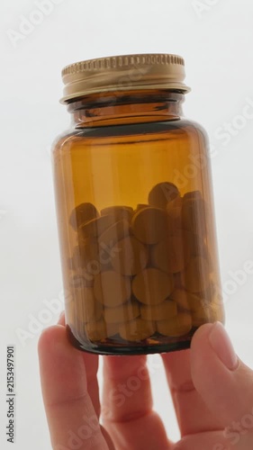 Hand holding amber glass bottle pills vitamins medicine supplements healthcare pharmacy closeup vertical video