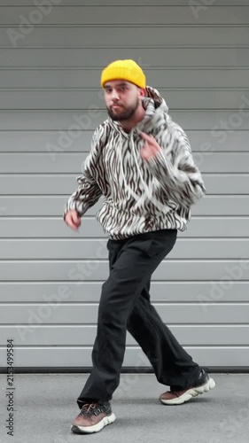 Young man freestyle street dance urban style casual streetwear yellow beanie energetic dance pose hip hop dancer vertical video social media content